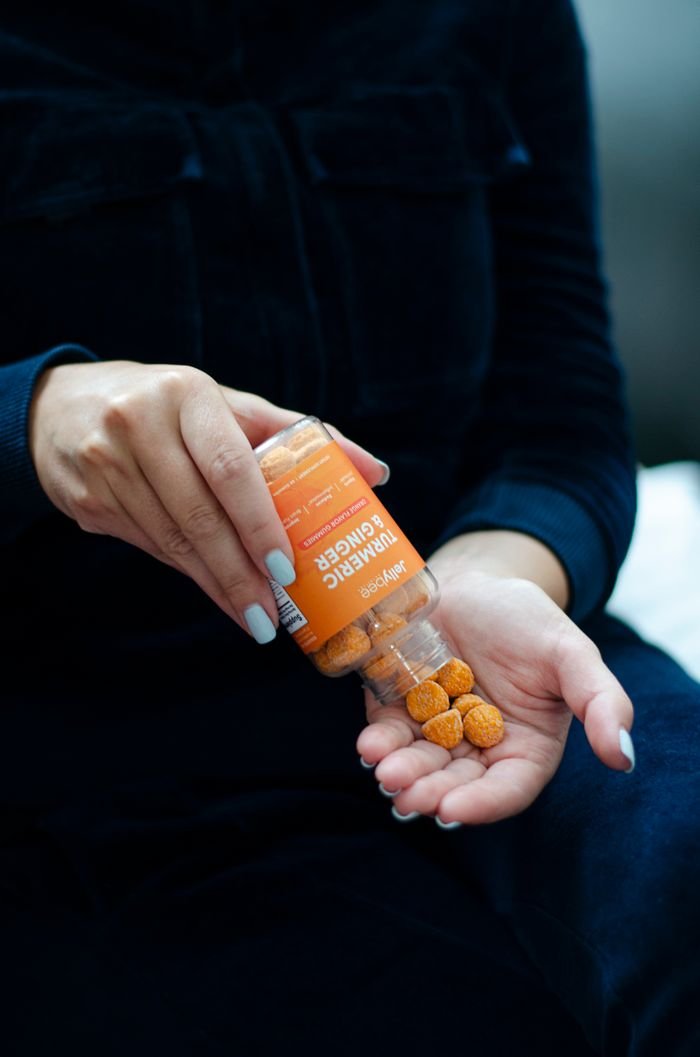 Home Close-up of a person pouring turmeric ginger gummies into their hand.