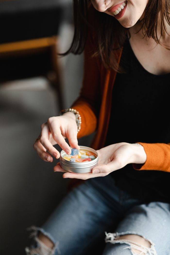 Home Close-up of a woman holding CBD gummies in a tin, symbolizing relaxation and wellness.